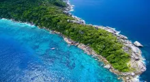 Aerial view of a lush green coastline meeting turquoise waters in Phuket.