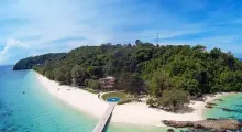 Scenic view of a lush island in Phuket with a beach, clear water, and a swimming pool.