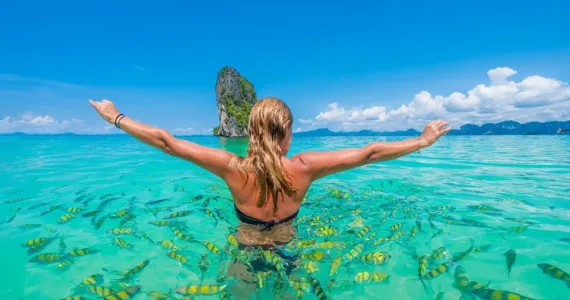 Женщина плавает в прозрачной воде на Пхукете среди ярких рыб.