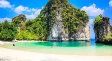 Stunning beach in Phuket with clear turquoise water and lush green mountains.