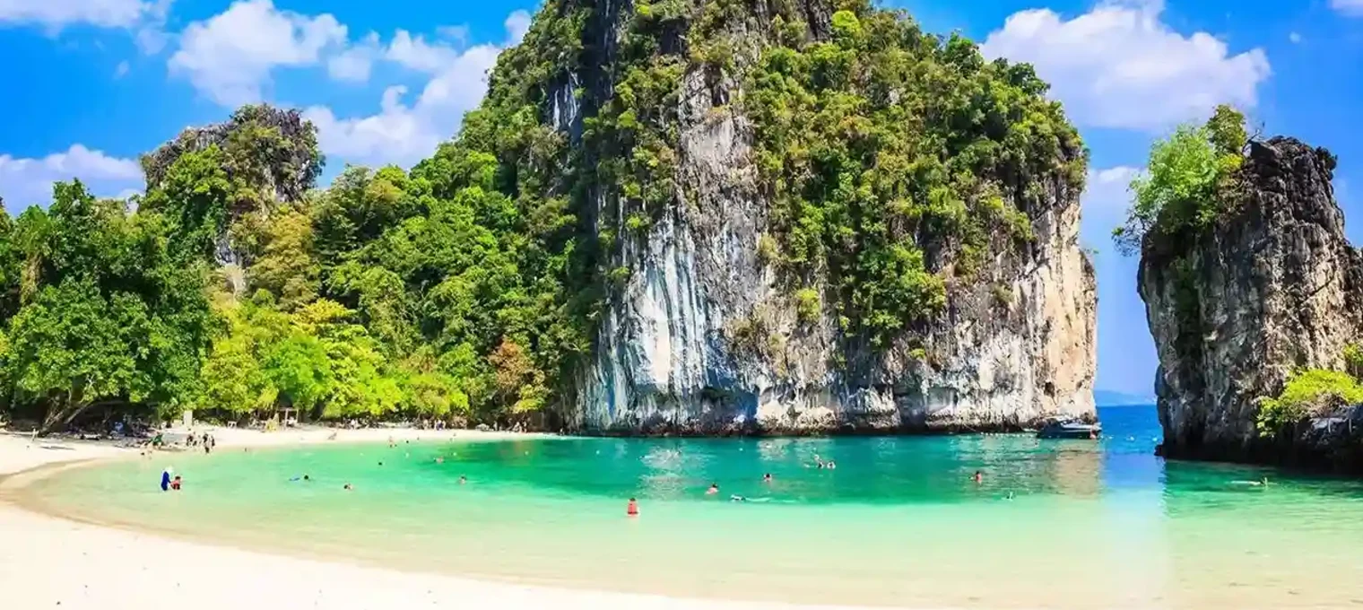 Stunning beach in Phuket with clear turquoise water and lush green mountains.