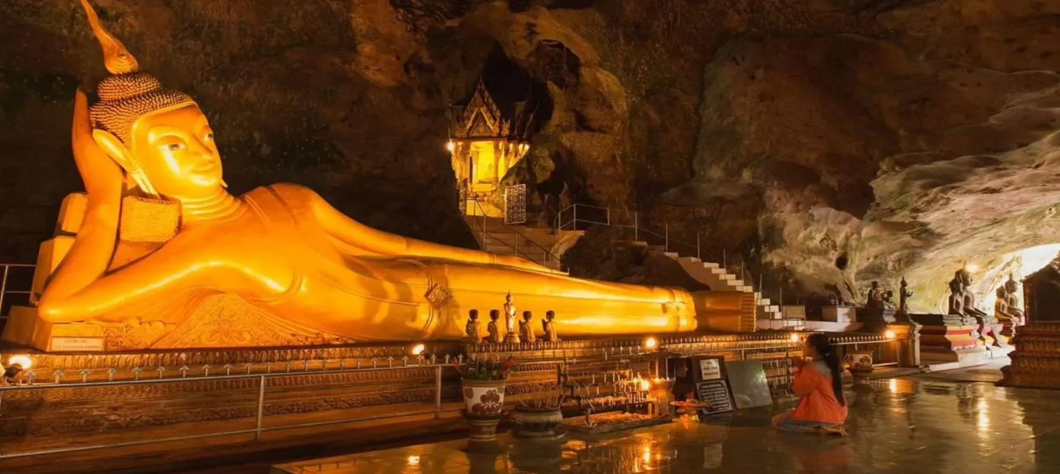 Golden reclining Buddha statue in a cave temple in Phuket, Thailand, with serene lighting.