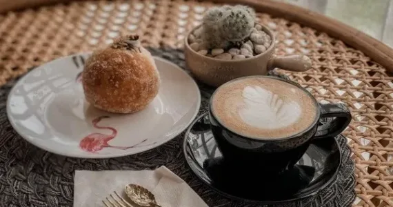 Кофе с латте-артом и пышкой на столе в кафе на Пхукете.