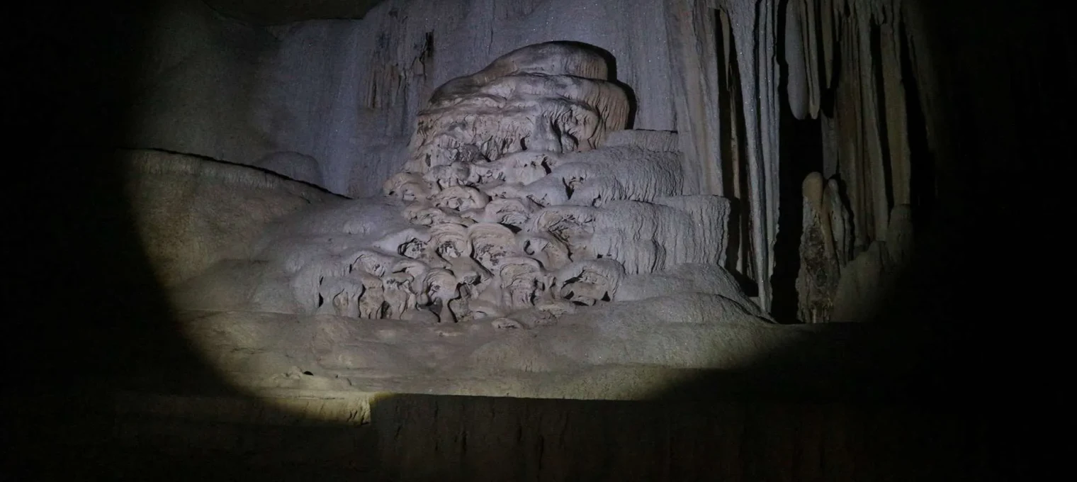 Stalactites and rock formations in a cave in Phuket, illuminated by a flashlight.