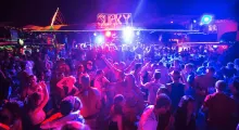 Crowd dancing at a vibrant night club in Phuket, illuminated by colorful lights.