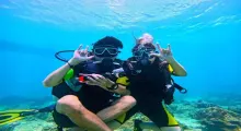 Two divers giving hand signals underwater in Phuket's clear blue waters.