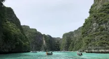 Scenic view of lush cliffs and turquoise waters in Phuket, Thailand, with boats.