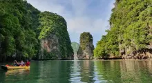 Kayakers exploring tranquil waters amid lush green cliffs in Phuket, Thailand.