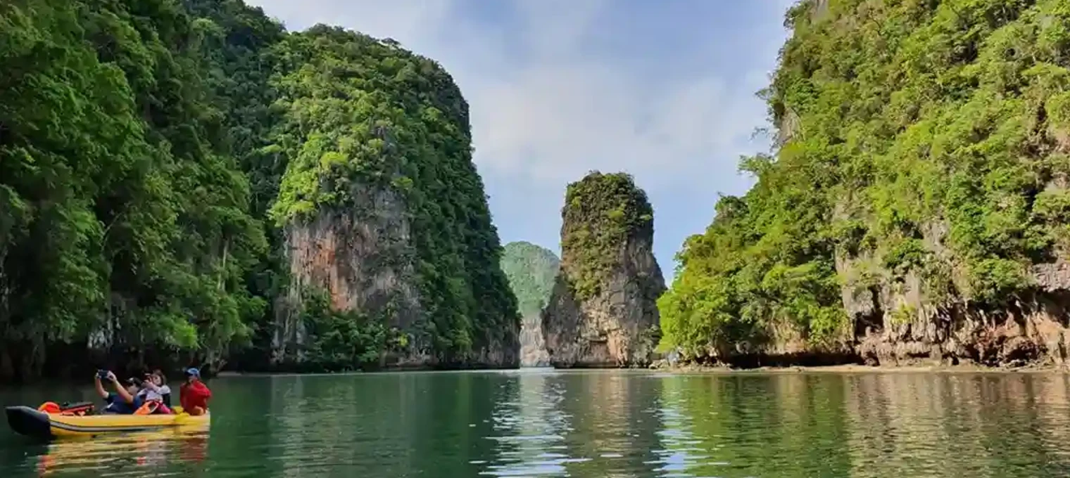 Kayakers exploring tranquil waters amid lush green cliffs in Phuket, Thailand.
