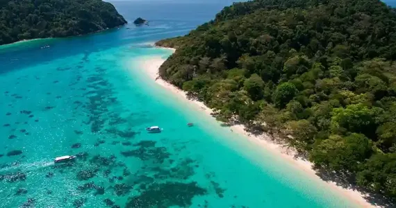 Aerial view of a tropical beach in Phuket with turquoise waters and lush greenery.