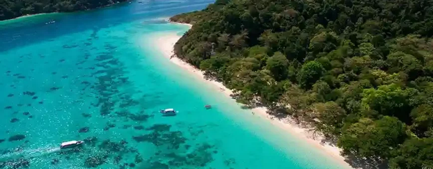 Aerial view of a tropical beach in Phuket with turquoise waters and lush greenery.