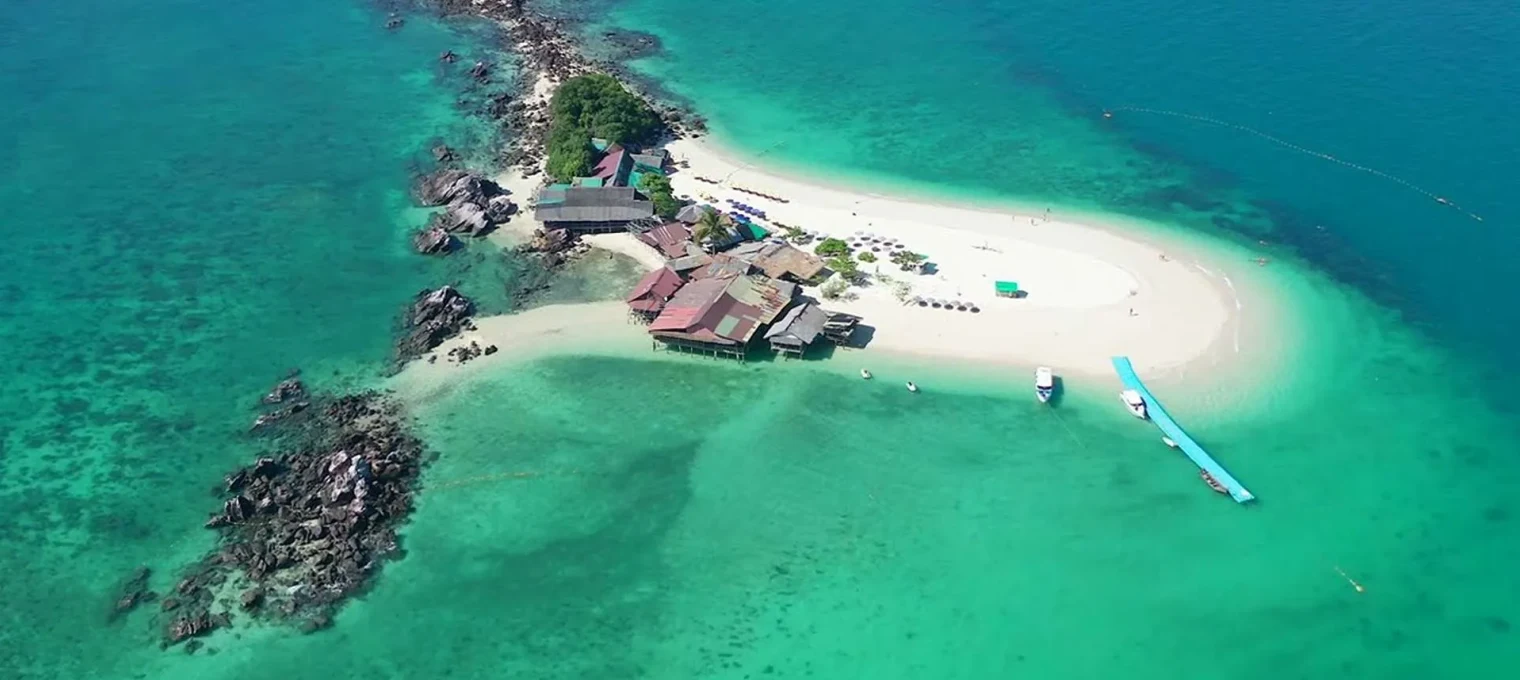 Aerial view of a tropical island in Phuket with clear turquoise waters and sandy beach.