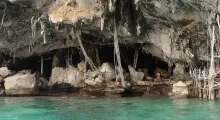 Rocky cave entrance by clear turquoise water in Phuket, Thailand.