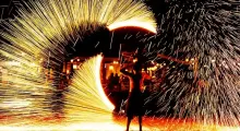 Fire performer creates a stunning display of sparks against a night sky in Phuket.