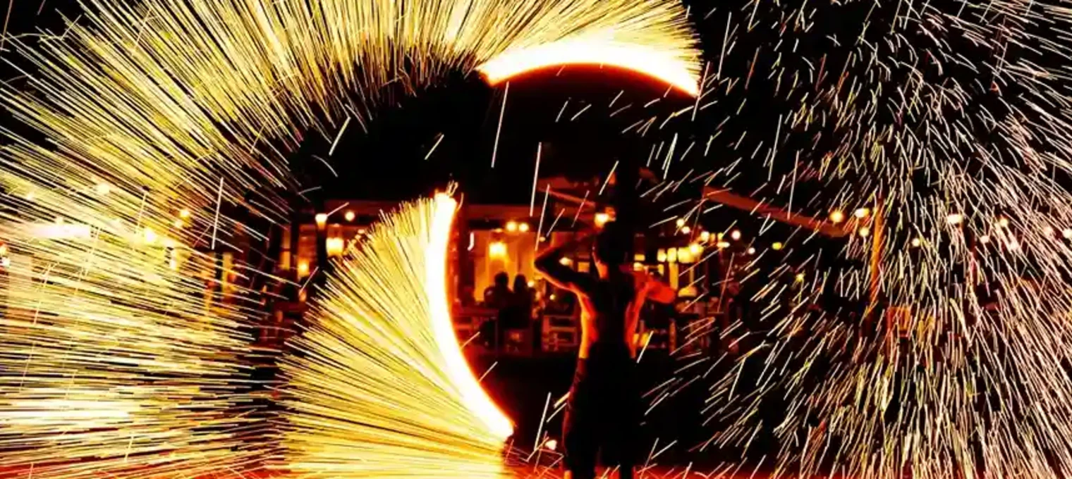 Fire performer creates a stunning display of sparks against a night sky in Phuket.