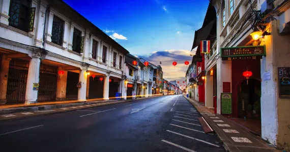 Empty street in Phuket with Chinese lanterns and colorful old buildings at sunset.