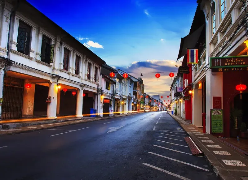 Empty street in Phuket with Chinese lanterns and colorful old buildings at sunset.