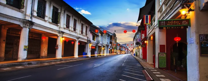 Empty street in Phuket with Chinese lanterns and colorful old buildings at sunset.