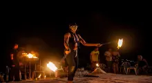 Fire dancer performing at night on a beach in Phuket, surrounded by an enthusiastic audience.