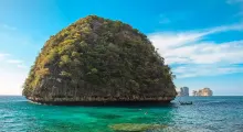 Scenic view of a tropical island in Phuket with clear blue waters and lush greenery.