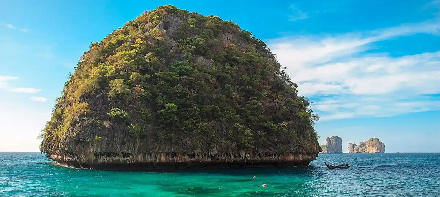 Scenic view of a tropical island in Phuket with clear blue waters and lush greenery.