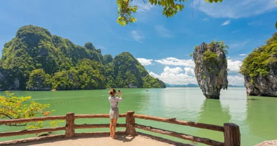 Женщина фотографирует красивый пейзаж с морем и скалами в Пхукете.