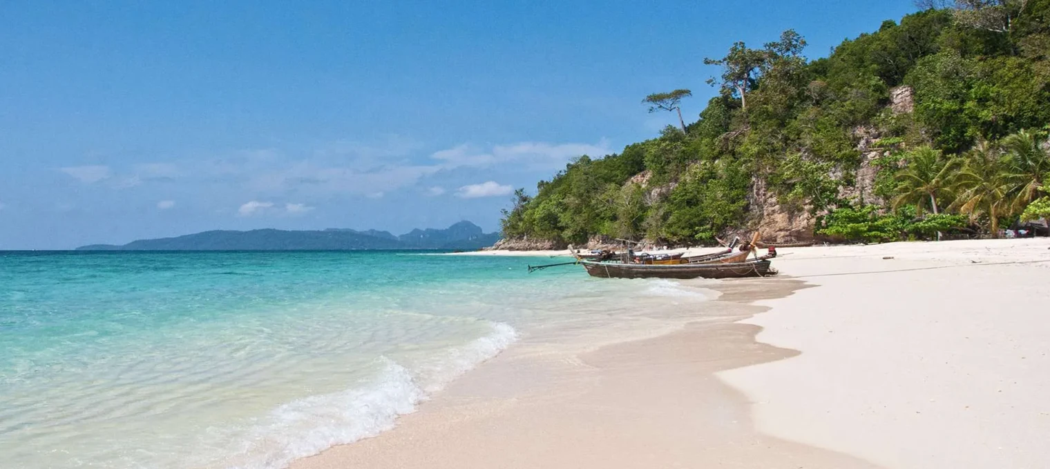 Idyllic beach in Phuket with turquoise waters, sandy shore, and lush greenery.