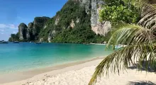 Beautiful beach in Phuket with turquoise waters, sandy shore, and lush green cliffs.