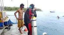 Diver prepares to dive while another person smiles on the boat in Phuket. Sunny day at sea.