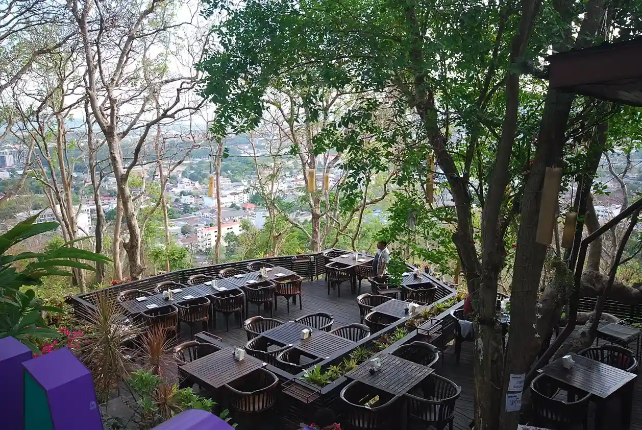 Сады и столы на открытой террасе с видом на город в Пхукете.