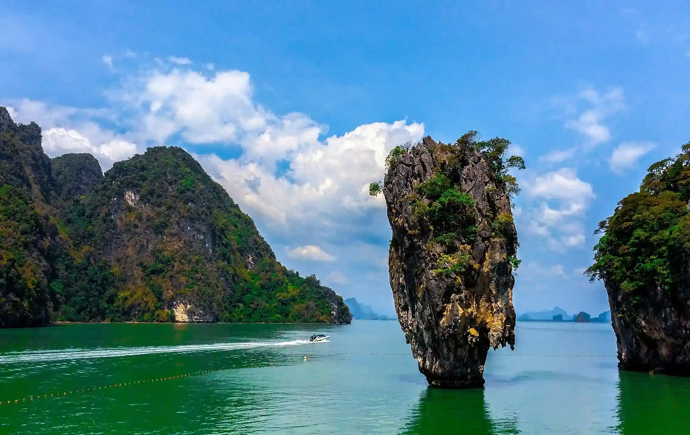 Scenic view of limestone cliffs and a small boat near a rocky outcrop in Phuket.