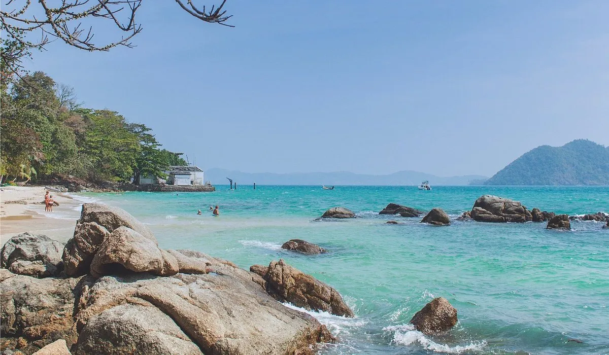 Пляж на Пхукете с прозрачной водой и скалами на фоне хрустального неба.