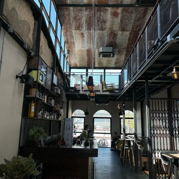 Modern cafe interior in Phuket with large windows, industrial decor, and a cozy atmosphere.