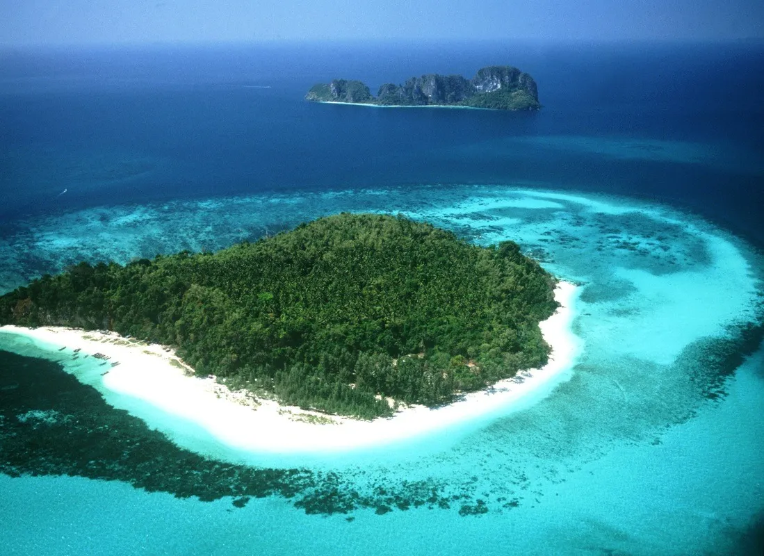Aerial view of a tropical island in Phuket with white sandy beach and turquoise waters.