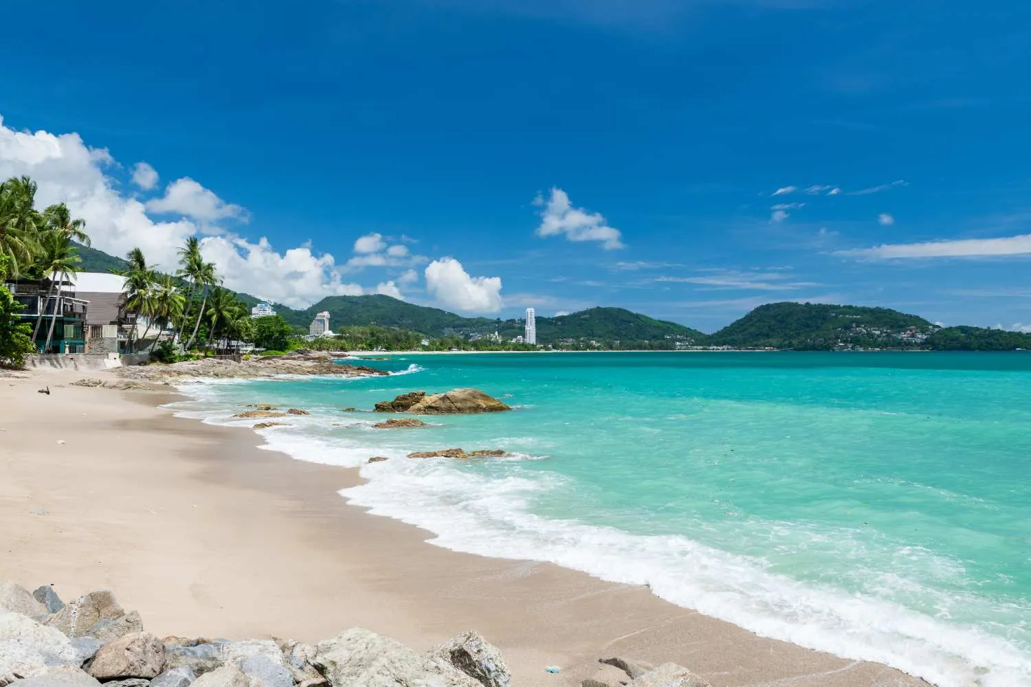 Stunning beach view in Phuket with turquoise waters and palm trees under a blue sky.