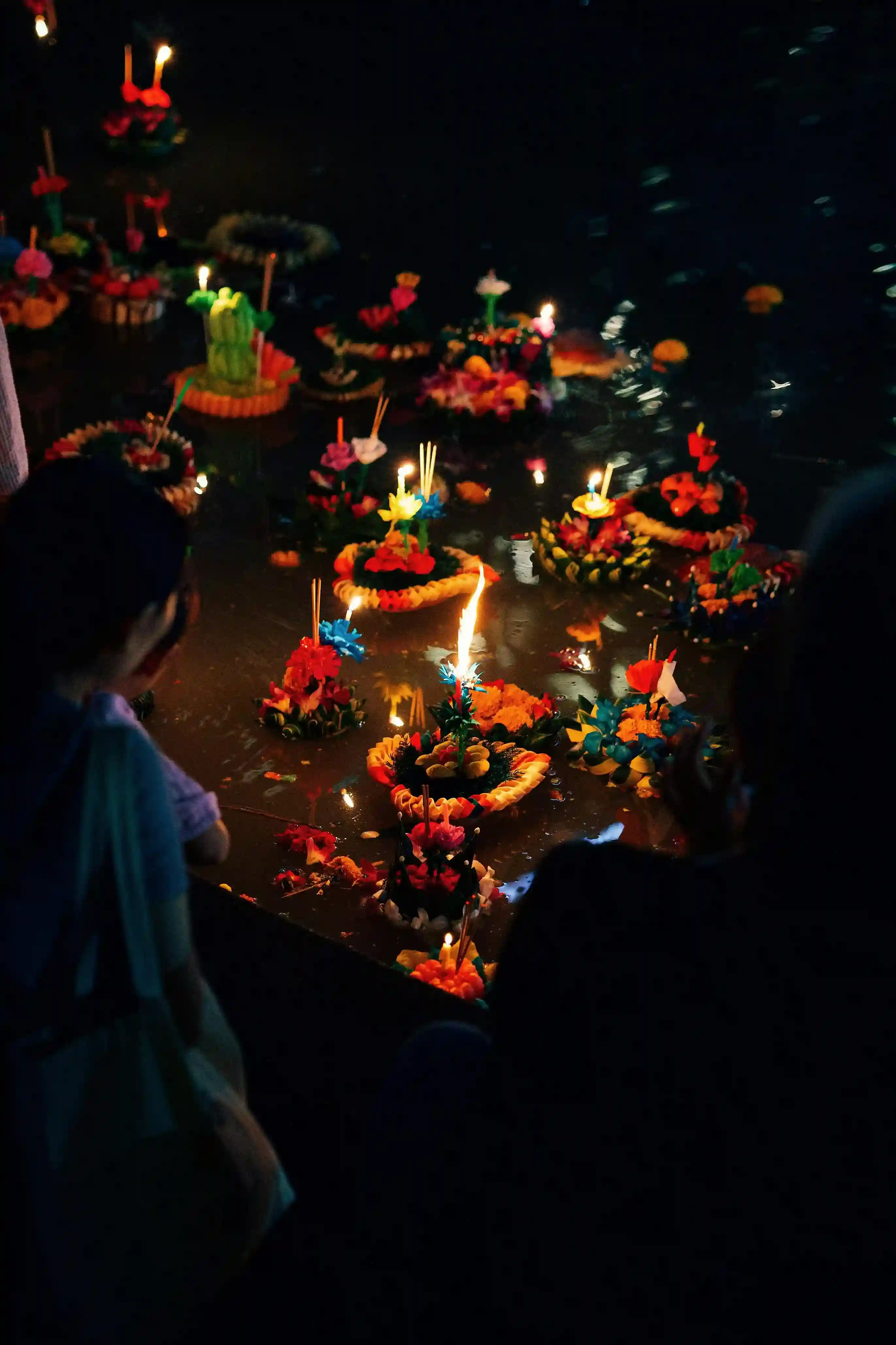Colorful floating lanterns and candles illuminate the water during a festival in Phuket.