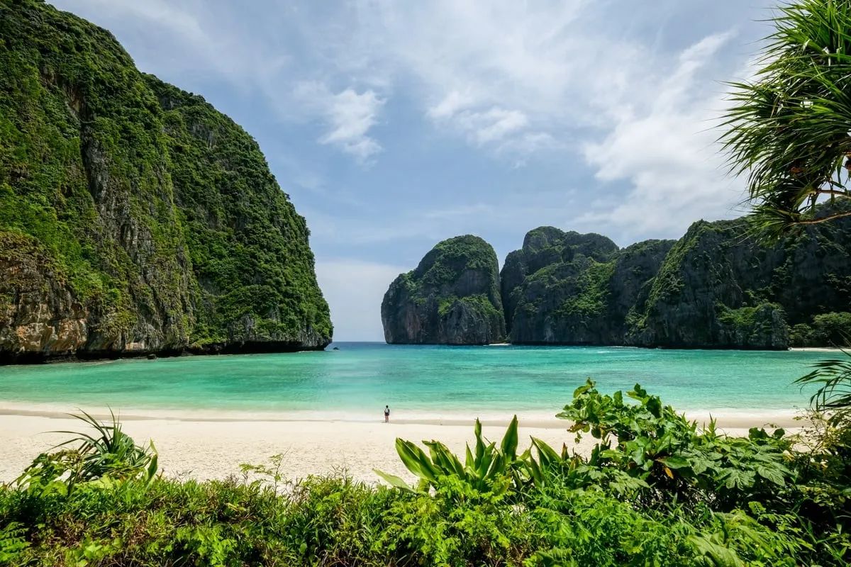 Scenic view of a tropical beach in Phuket with turquoise water and lush green cliffs.