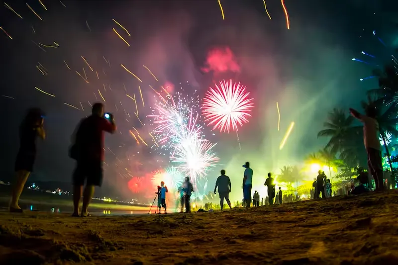 Фейерверк над пляжем в Пхукете, люди наслаждаются зрелищем ночью.