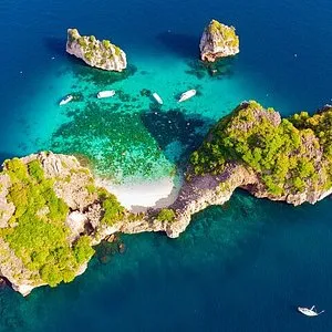 Aerial view of turquoise waters and rocky islands near a sandy beach in Phuket.