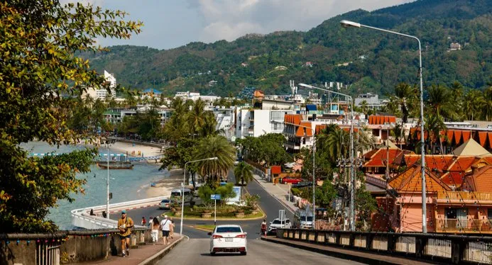 View of a street in Phuket with palm trees, beaches, and buildings along the coastline.
