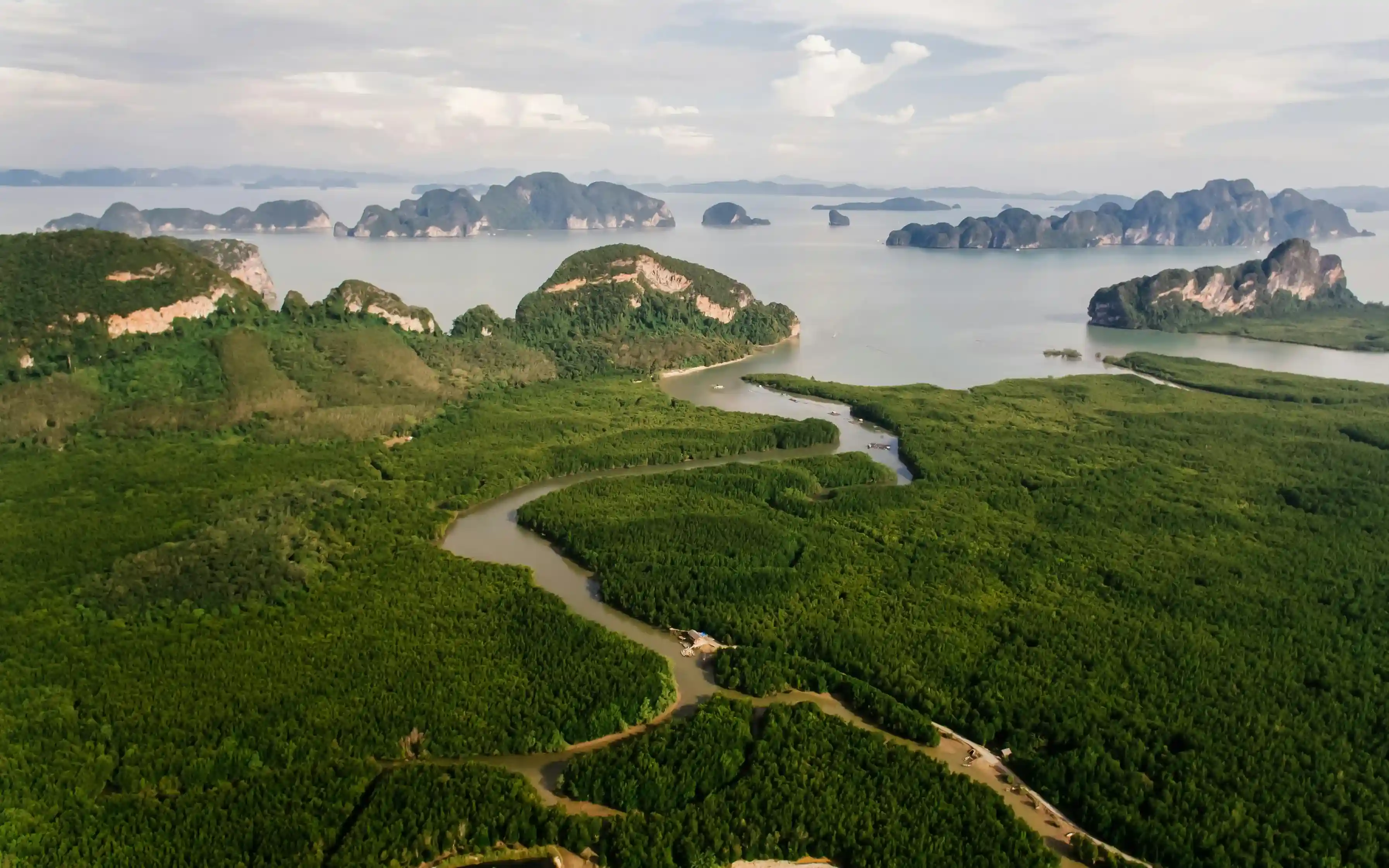 Aerial view of lush mangroves and islands in Phuket, with a winding river through greenery.
