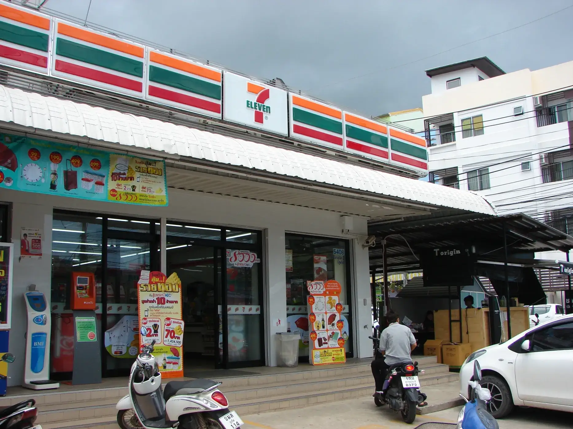 Магазин 7-Eleven на улице в Пхукете, жилые здания на заднем плане.
