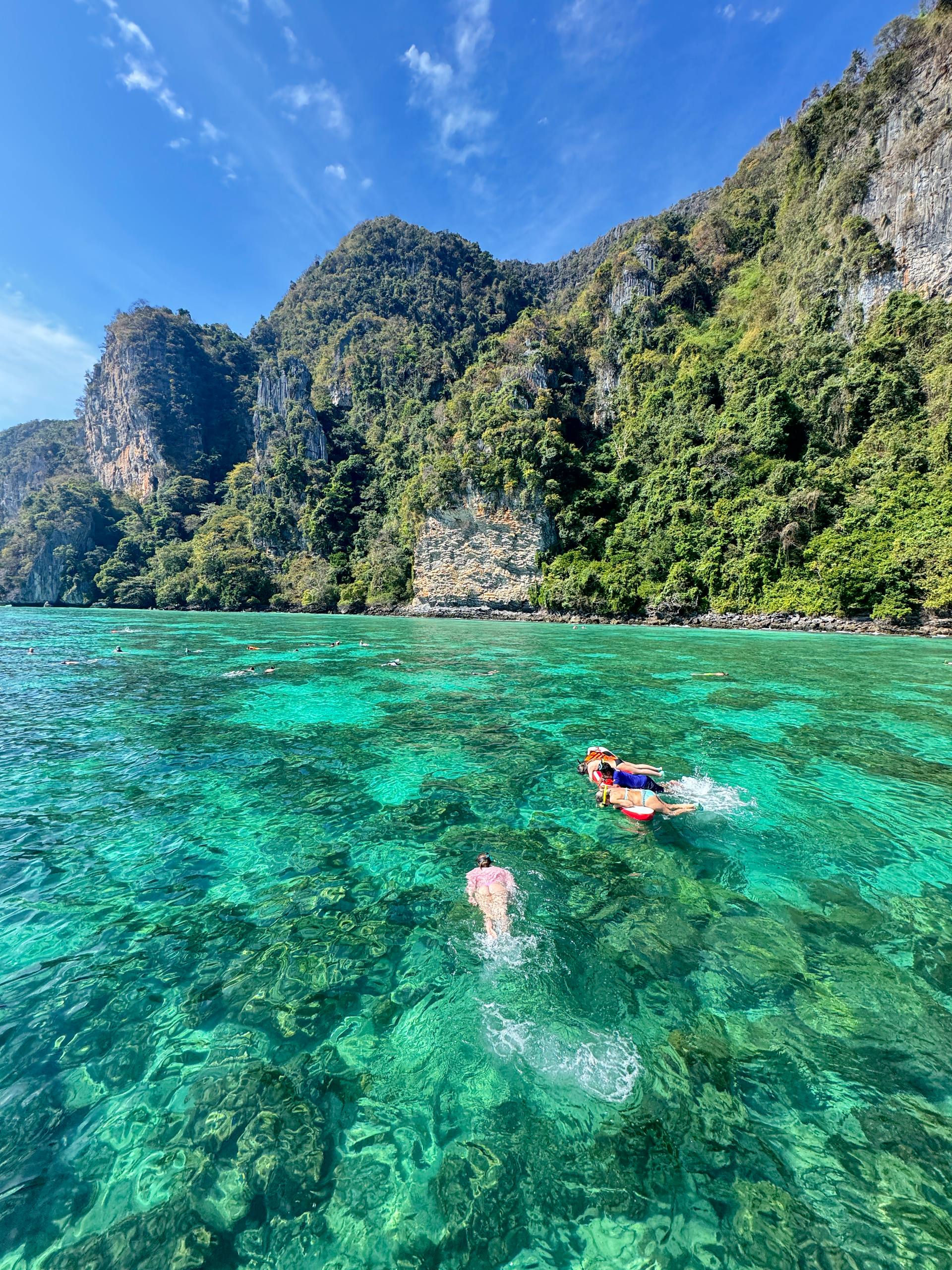 Swimmers explore clear sky waters near Phi Phi, Thailand.