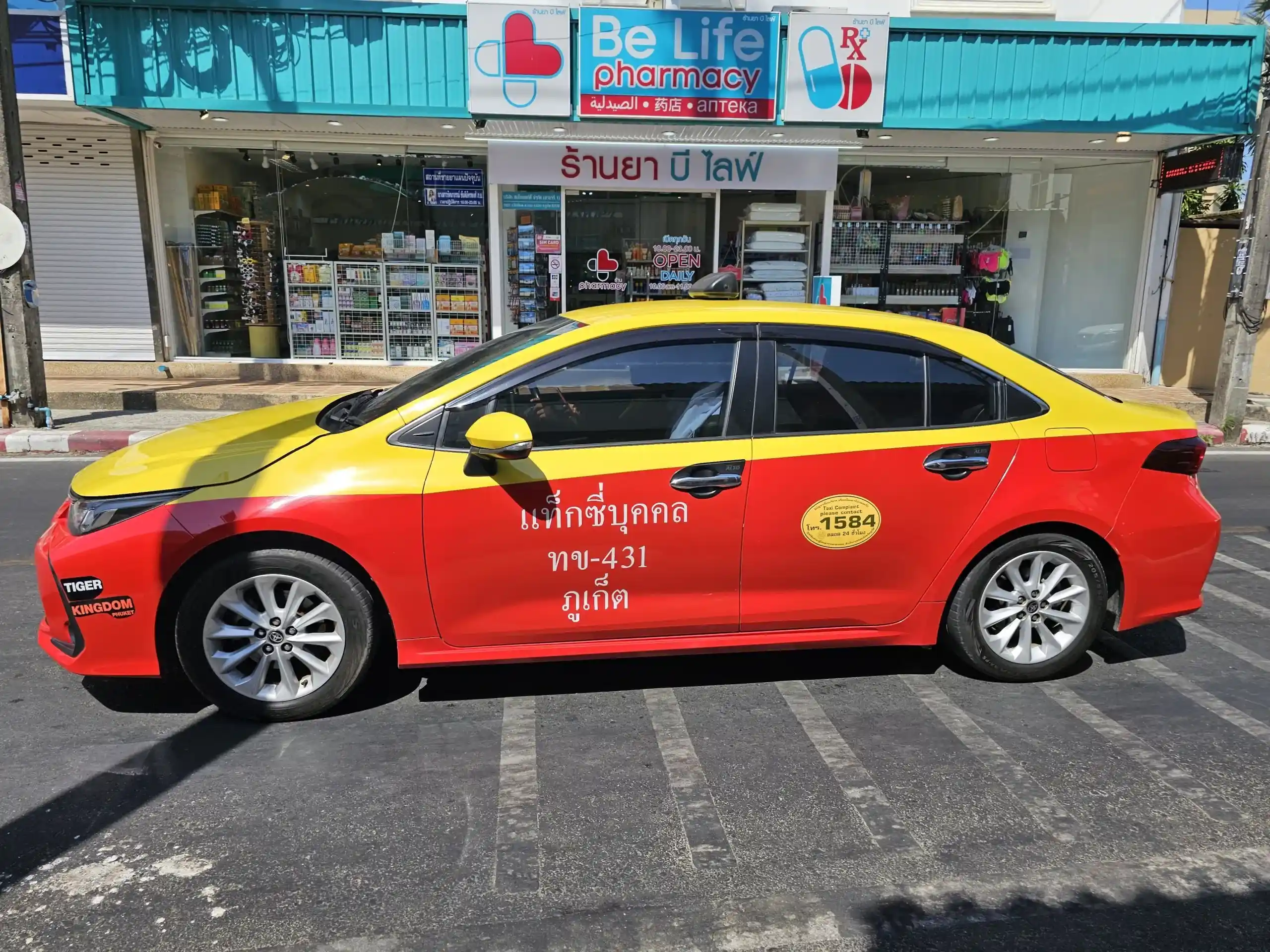 Bright red and yellow taxi parked near a pharmacy in Phuket, Thailand.