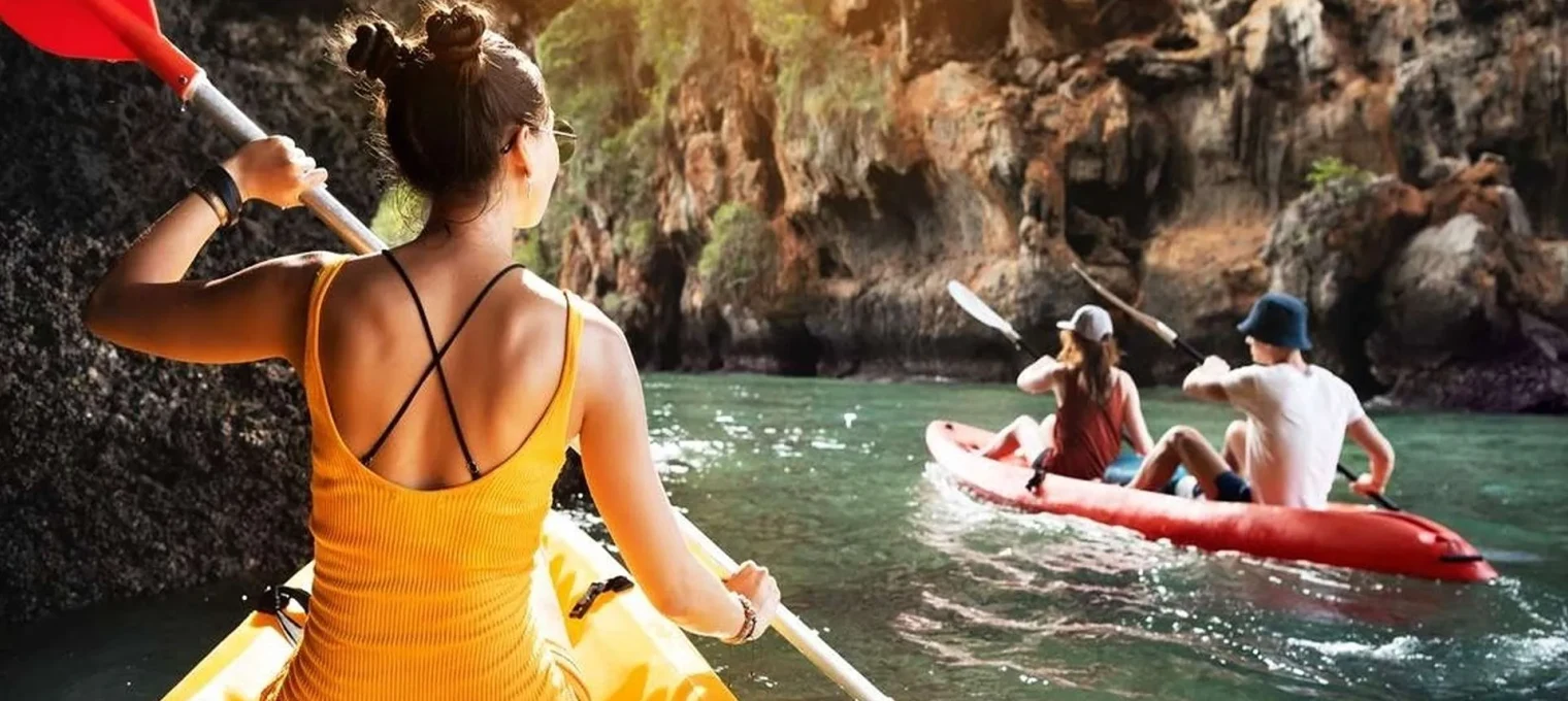 A woman paddles a kayak in Phuket, with two others kayaking nearby in the scenic waters.