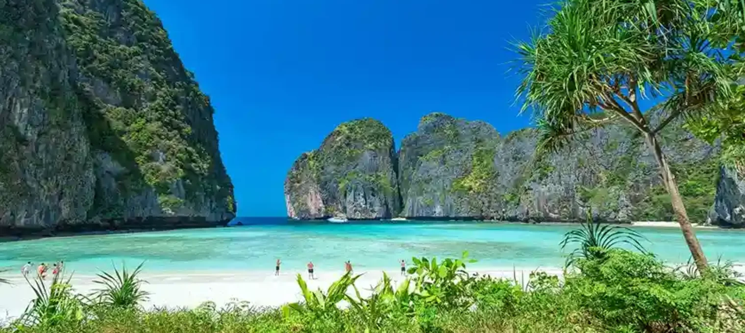 Tropical beach in Phuket with cliffs and clear turquoise waters on a sunny day.