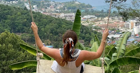 Девушка на качелях с видом на залив Пхукета и городскую панораму.