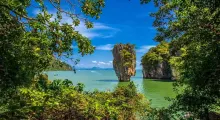 Lush greenery frames a stunning view of rocky islands in the turquoise waters of Phuket.