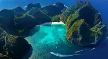 Aerial view of Phuket's turquoise water bay surrounded by lush green mountains.