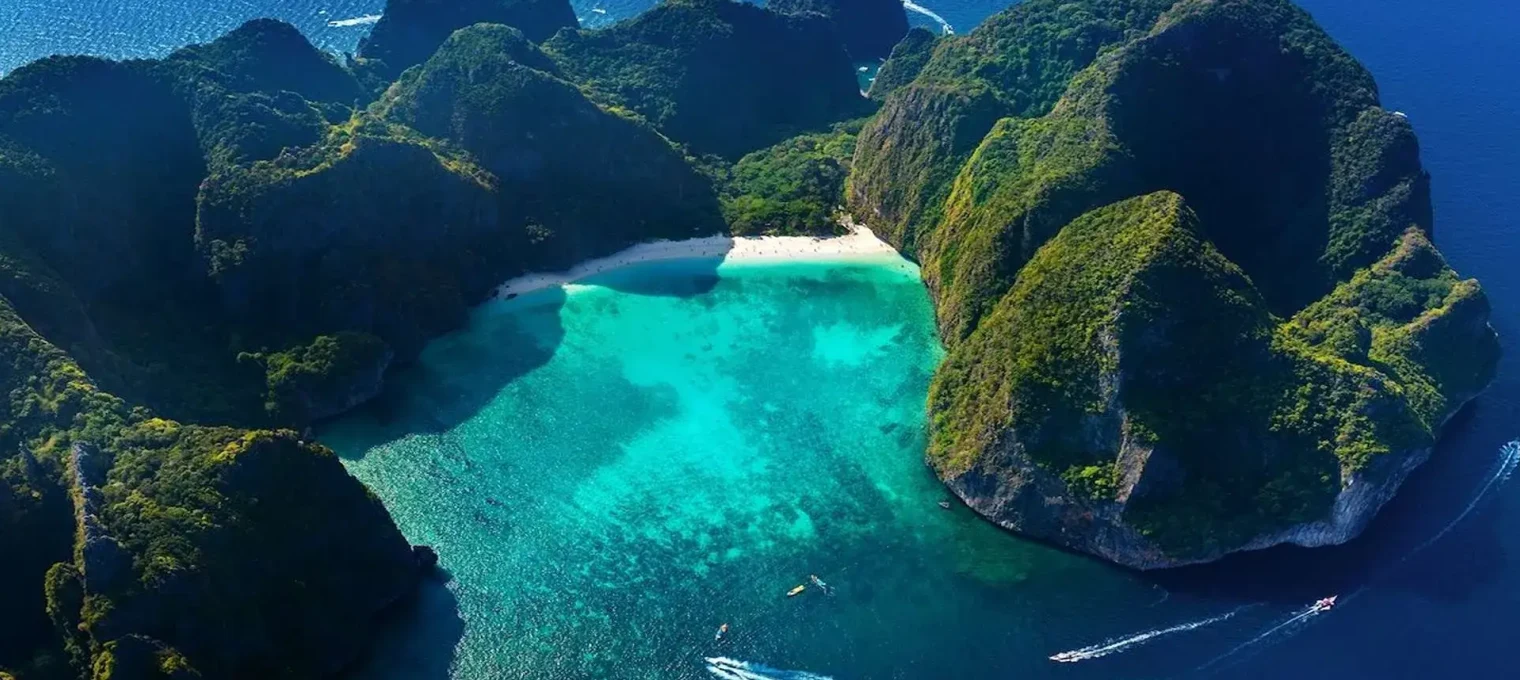 Aerial view of Phuket's turquoise water bay surrounded by lush green mountains.